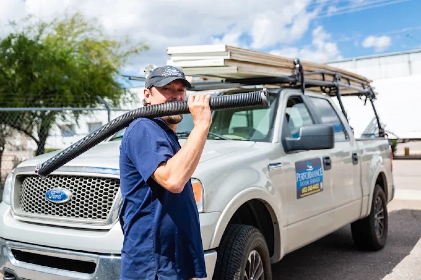 A technician carrying a garage door cable past a loaded service truck